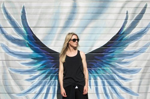 A woman standing in front of wings painted on a wall