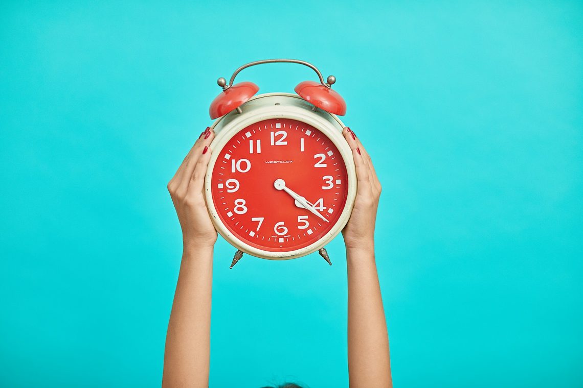 Woman holding up a red and white clock