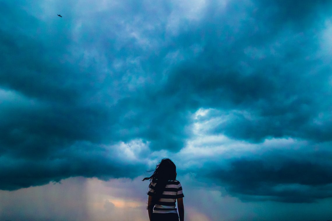 A woman standing in front of a stormy sky