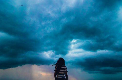 A woman standing in front of a stormy sky