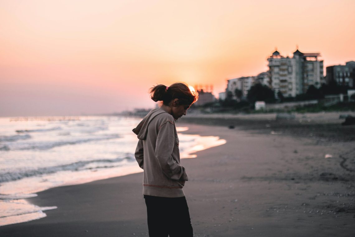 Woman looking down and walking on the beach