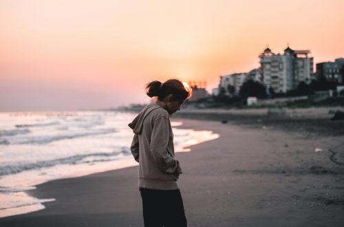Woman looking down and walking on the beach