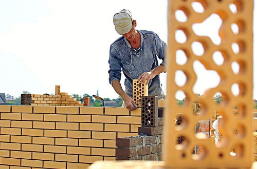 Man laying brick to build a wall