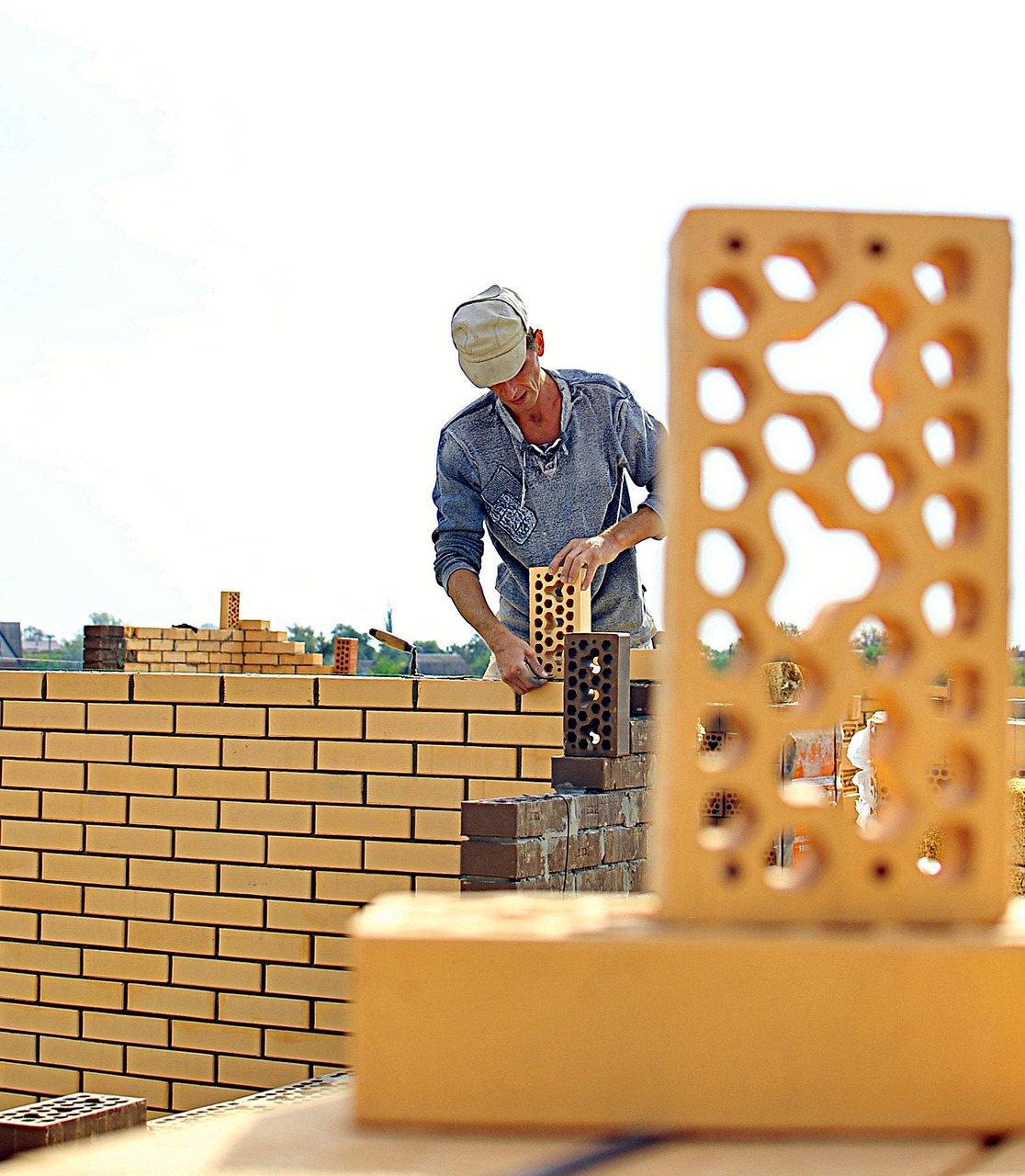 Man laying brick to build a wall