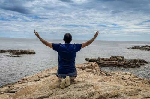 man kneeling on a rock by the sea