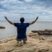 man kneeling on a rock by the sea