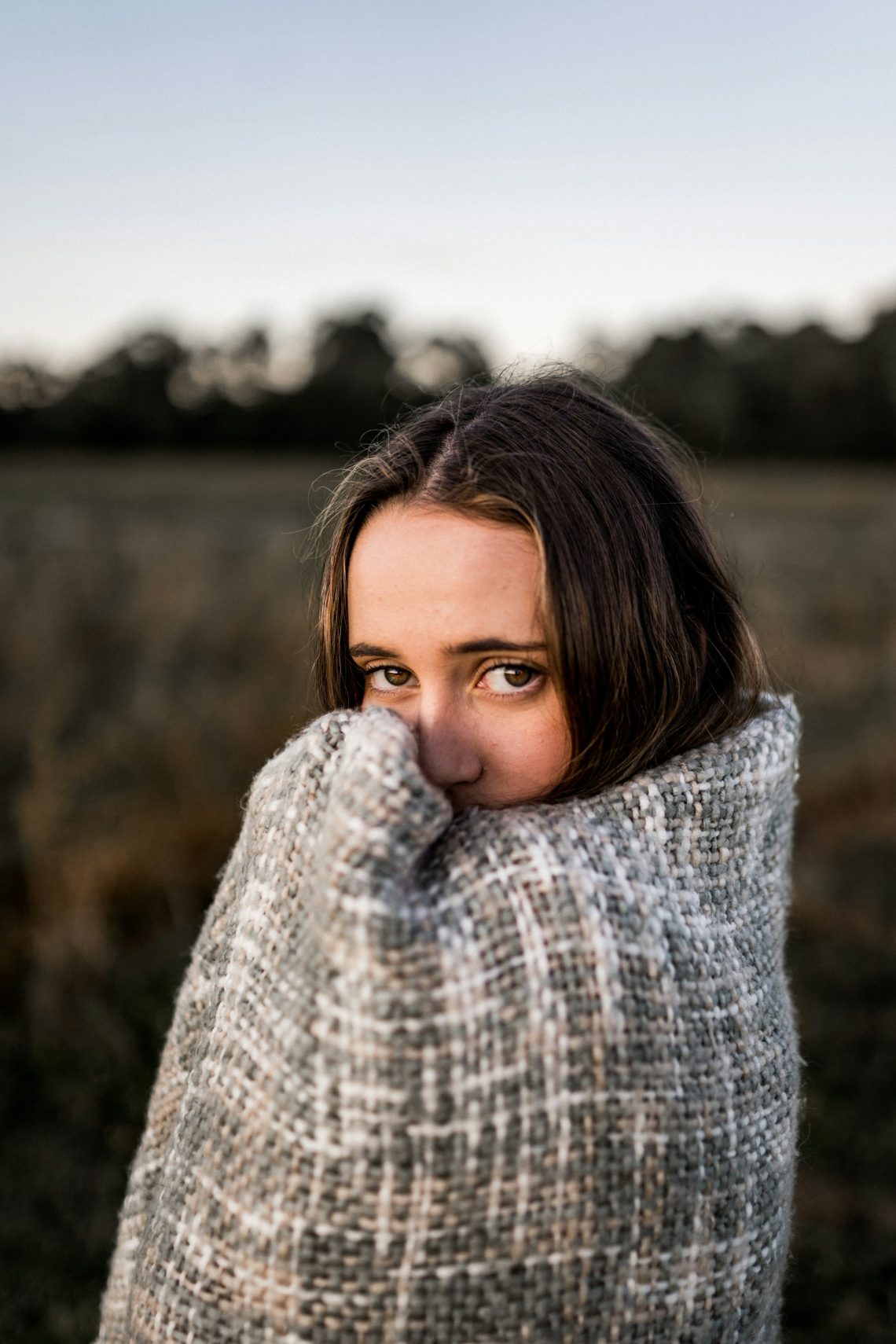 A woman standing and wrapped in a blanket